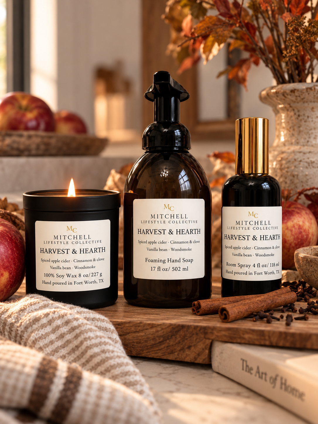 Fall soy candles and a reed diffuser on a wood table with autumn leaves