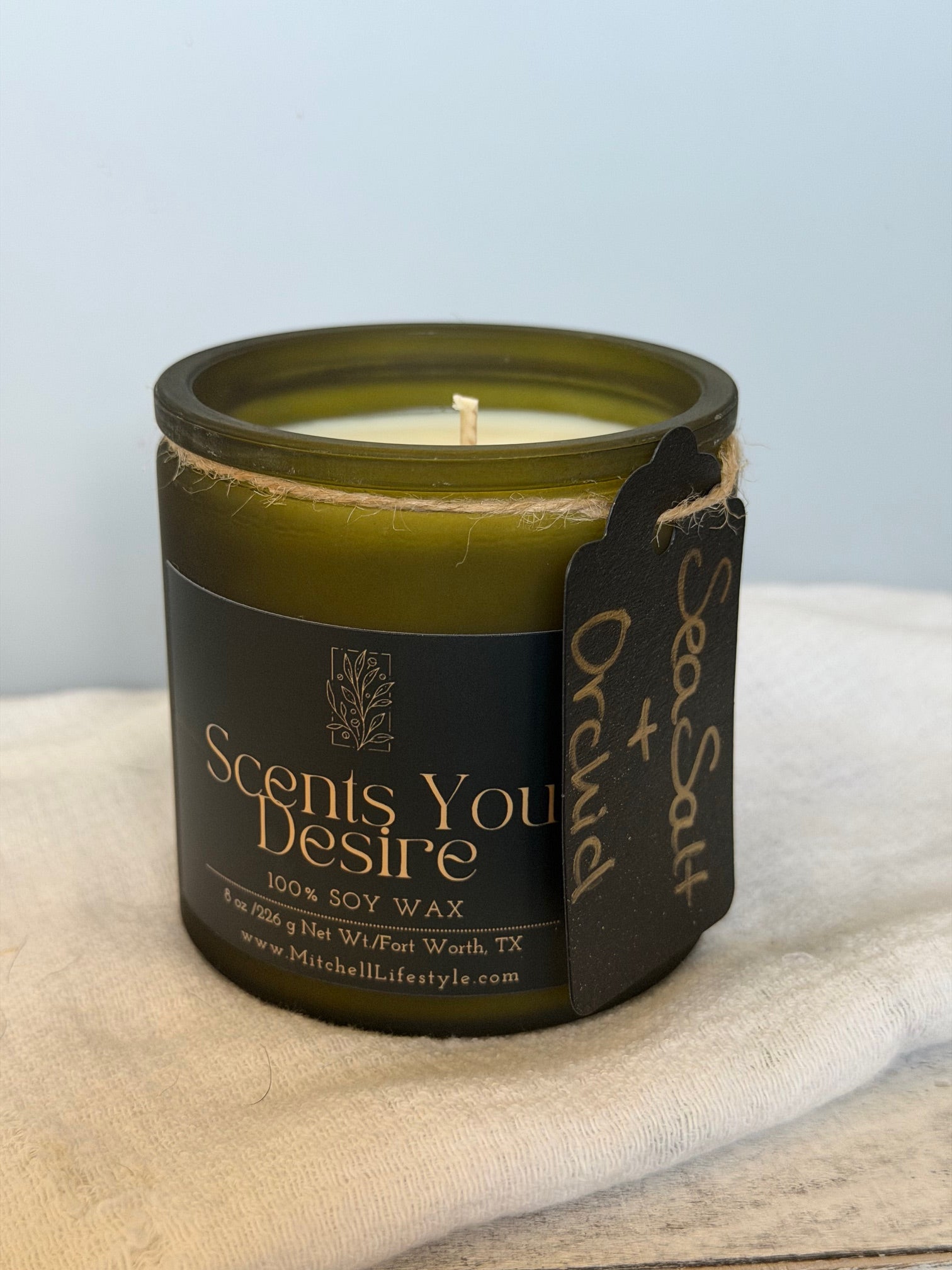 Sea Salt and Orchid luxury candle by Scents You Desire in a bright, airy room