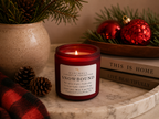 Snowbound soy candle in a red vessel, lit, on a styled tabletop